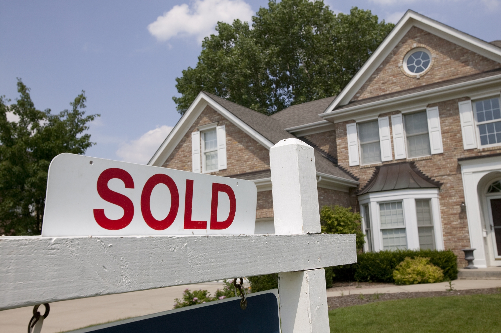 Sold house sign in Midwest suburban setting. Focus on sign.